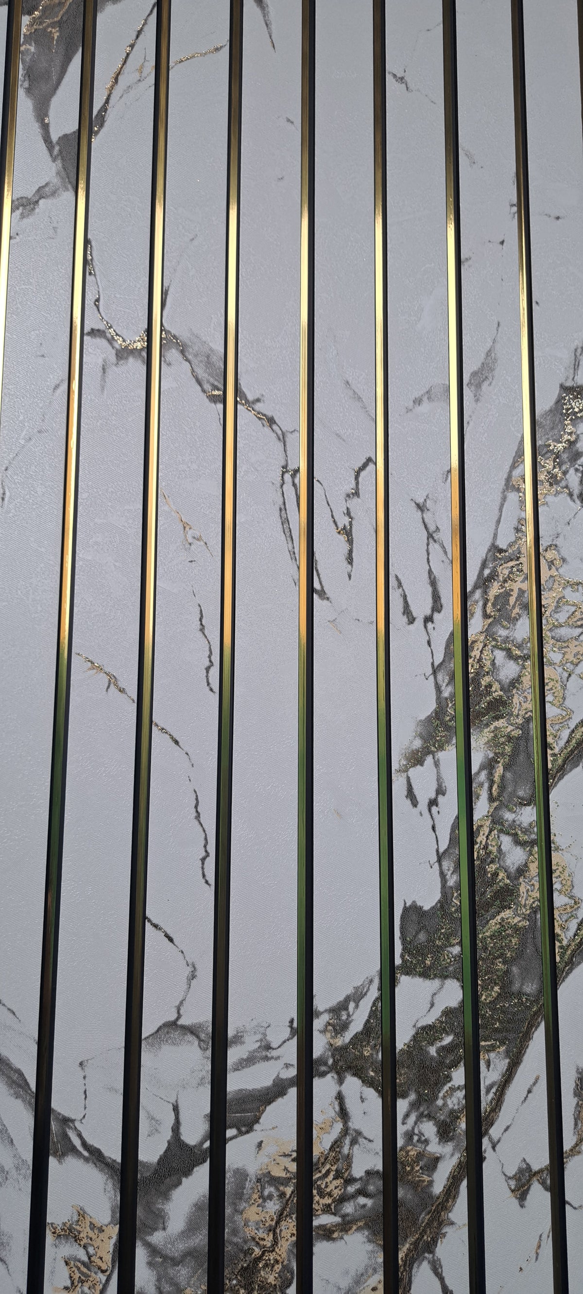 Vertical gold metal rods overlaid on a white marble-patterned background with gray and gold veining.
